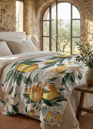Bedroom with stone walls and large windows, featuring a bed with a lemon-patterned duvet.
