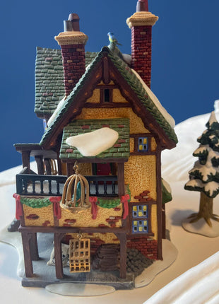 Illuminated Porcelain Christmas Village "Wingham Lane Parrot Seller" House" by Dept 56. and Woman Holding Bird Cage, Dickens Village, 1999.