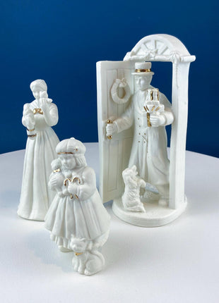 White Porcelain Figurines of Santa & His Family Celebrating Christmas in Front of Fireplace. Illuminated Fireplace and Tree. Mantel Display.